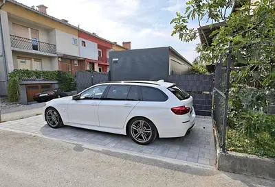 a white car parked in front of a fence at Relax Tiny House Ljubljana in Ljubljana