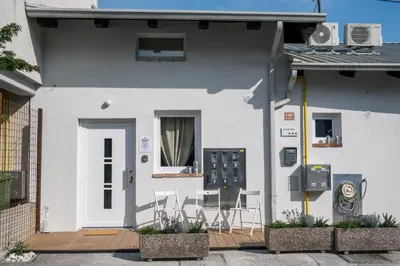 a white house with a table and chairs on a porch at Garage Apartments in Nova Gorica
