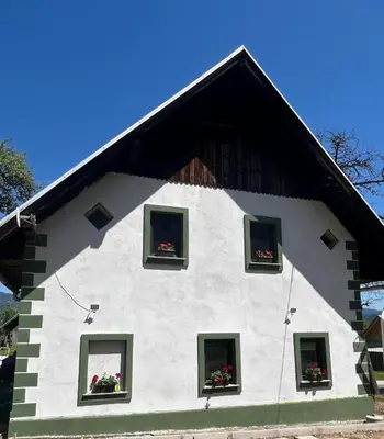 a white house with flowers in the windows at Bohinj Countryside House in Bohinjska Bistrica