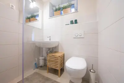 a white bathroom with a toilet and a sink at Castle Rock Bled apartment in Bled