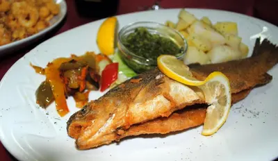 a plate of food with fish and potatoes and vegetables at Pri Vidrgarju in Vače