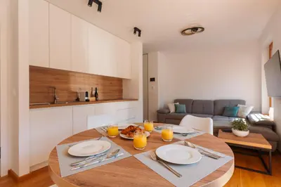 a kitchen and dining room with a wooden table with glasses of orange juice at Alpine Bliss Apartment Kranjska Gora in Kranjska Gora