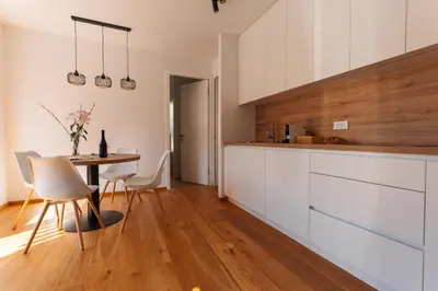 a kitchen with white cabinets and a table with chairs at Alpine Bliss Apartment Kranjska Gora in Kranjska Gora