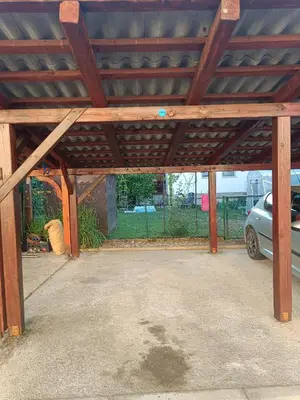 a garage with a wooden roof with a car parked under it at Lovely 1- bedroom apartment in Skofja Loka in Škofja Loka