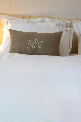 a pillow with the letter m on it sitting on a bed at Chalet Bohinj Bliss Wellness and view of Triglav in Bohinj