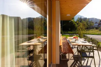 a patio with tables and chairs on a balcony at Chalet Bohinj Bliss Wellness and view of Triglav in Bohinj