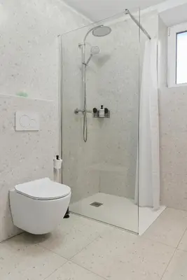 a white bathroom with a shower and a toilet at Casa 1920 Apartment in Bovec