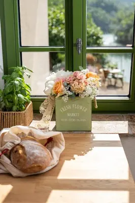 a box of flowers and a loaf of bread on a table at Apartma FRIDA in Most na Soči