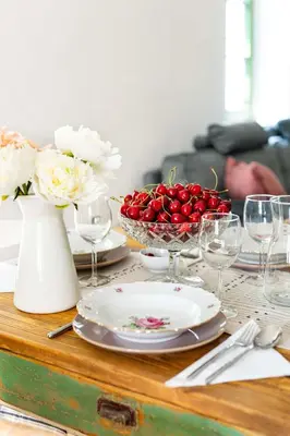 a table with plates and glasses and a bowl of cherries at Apartma FRIDA in Most na Soči