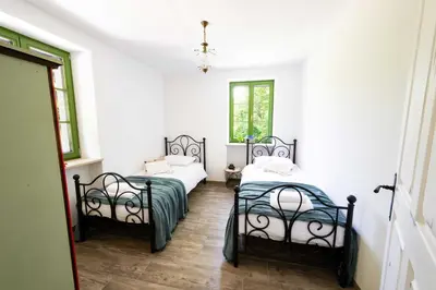 two beds in a room with white walls and wooden floors at Apartma FRIDA in Most na Soči