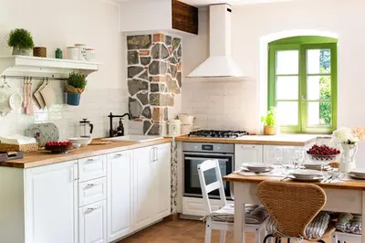 a kitchen with white cabinets and a table at Apartma FRIDA in Most na Soči