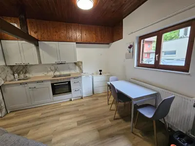 a kitchen with white cabinets and a table and chairs at Studio R in Ljubljana