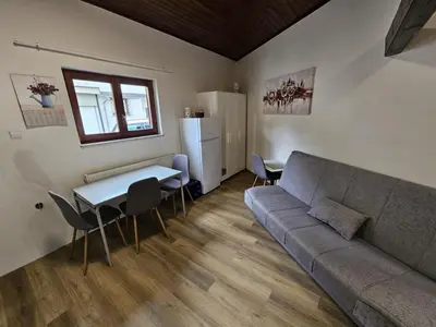 a living room with a couch and a table and a refrigerator at Studio R in Ljubljana