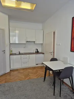 a kitchen with white cabinets and a table and chairs at Ritual Studio City Center in Ljubljana