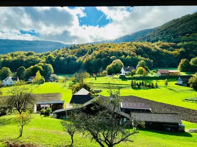 a farm in the middle of a field with mountains in the background at Minicottage Casa de Lipa in Kostanjevica na Krki