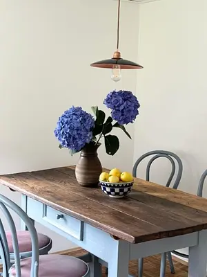 a table with a vase of blue flowers and a bowl of lemons at Maria's Orchard Cottage - Nature Retreat in Slovenia in Rogaška Slatina