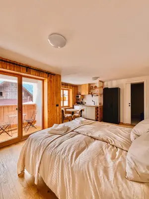 a bedroom with a large bed and a kitchen at Maison Lenka in Rateče