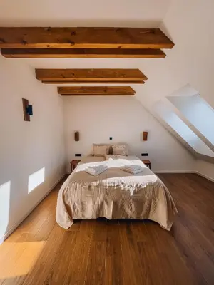 a bedroom with a bed in a room with wooden floors at Maison Lenka in Rateče