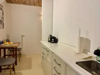 a white kitchen with a sink and a table at Vila Kralj in Podčetrtek