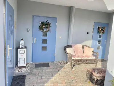 a living room with a blue door and a chair at Vila Kralj in Podčetrtek