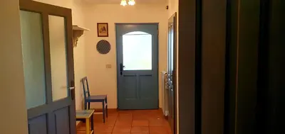 a hallway with a blue door and a table and chair at Karsolina in Štanjel