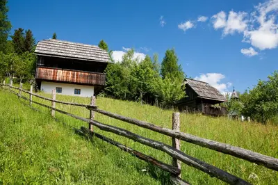 a wooden fence in front of a farm house at Domačija Koklej - Apartments Vintage Vacation in Luče