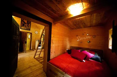 a bedroom with a red bed in a wooden room at Domačija Koklej - Apartments Vintage Vacation in Luče