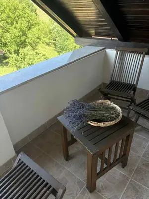 a porch with two chairs and a table with a wreath on it at Apartma Lavanda in Zavrč