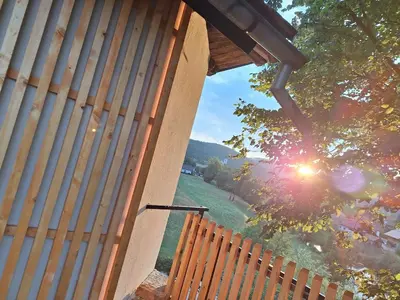 a view of the sun shining through a wooden fence at Hiška na skalci, The House on the Rock in Krka