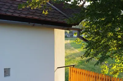 a white building with a black roof and a fence at Hiška na skalci, The House on the Rock in Krka