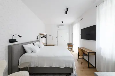 a white bedroom with a bed and a desk at Hiša Barbara in Celje