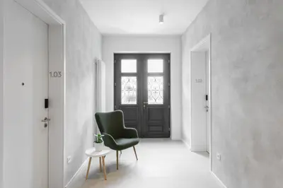 a white hallway with a green chair and a door at Hiša Barbara in Celje
