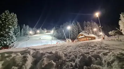 a snow covered ski slope at night with a lodge at Apartments Na Žagi in Železniki