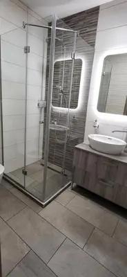 a bathroom with a glass shower and a sink at Apartments Na Žagi in Železniki