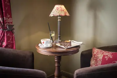 a table with a lamp and coffee cups on it at Hotel Pri mostu in Dolenjske Toplice