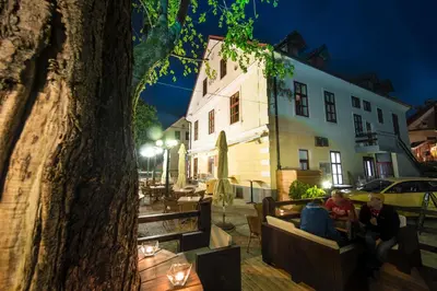 a group of people sitting on a bench next to a tree at Hotel Pri mostu in Dolenjske Toplice