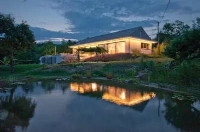 a house with a pond in front of it at Exklusive Premium-Lodge mit Pool, Sauna, Gästehaus