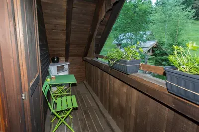 a porch with a green chair and a window at Brunarica Bled Zatrnik Pokljuka in Bled