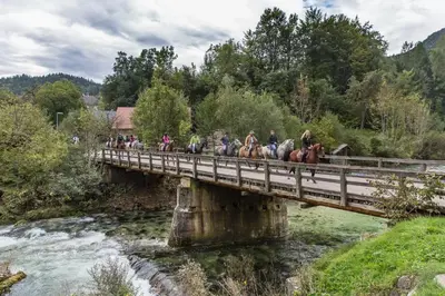 people riding horses on a bridge over a river at Brunarica Bled Zatrnik Pokljuka in Bled