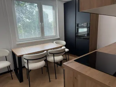 a kitchen with a wooden table and some white chairs at Moderno stanovanje - Ptuj in Ptuj