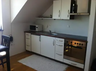 a kitchen with white cabinets and a sink and a stove at Andro's modern studio apartment in Ljubljana