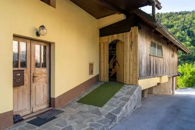 a house with a porch with a door and grass at Sobe na skednju in Bohinjska Bistrica