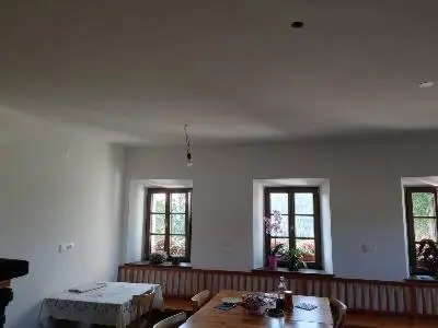 a living room with a table and three windows at Domačija Blaževc in Žiri