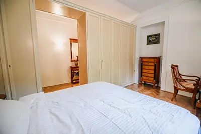 a bedroom with a white bed and a chair at Parkside Haven with 4 Bedrooms & free parking in Ljubljana