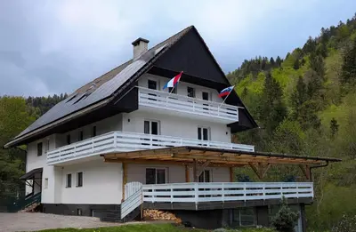 a large white building with two flags on it at Green Heart Suites in Podljubelj