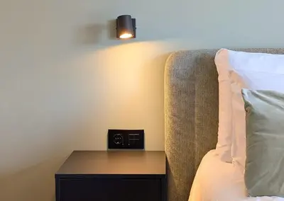 a bedroom with a bed with a nightstand with a alarm clock at Green Heart Suites in Podljubelj