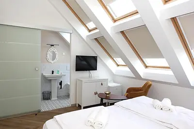 a attic bedroom with skylights and a room with two beds at D Rooms in Ljubljana