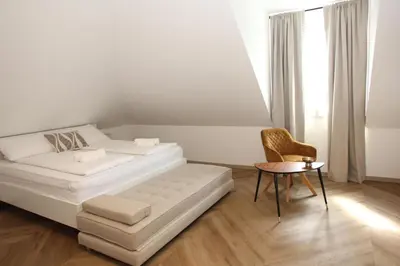 a white bedroom with a bed and a table at D Rooms in Ljubljana