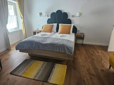 a bedroom with a large bed with a large headboard at Riva Residence in Old Town Ljubljana by the Cobblers' Bridge in Ljubljana