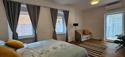 a bedroom with a bed and a couch and windows at Riva Residence in Old Town Ljubljana by the Cobblers' Bridge in Ljubljana